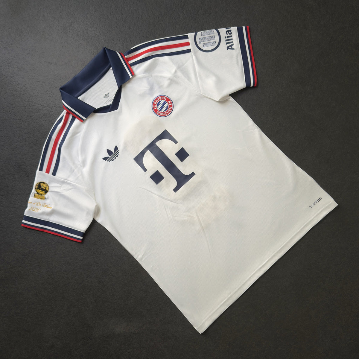 Front of the white Bayern Munich away jersey with the gold Ballon d'Or sleeve patch
