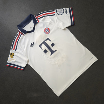 Front of the white Bayern Munich away jersey with the gold Ballon d'Or sleeve patch