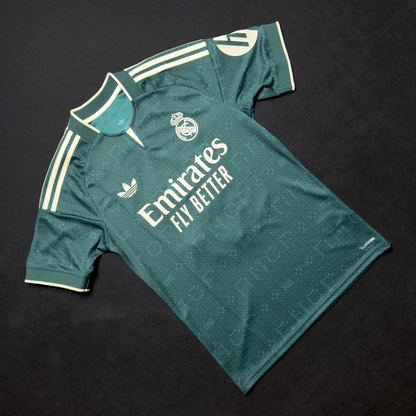 Front of the green adidas Real Madrid away jersey with the club crest and Emirates Fly Better sponsor