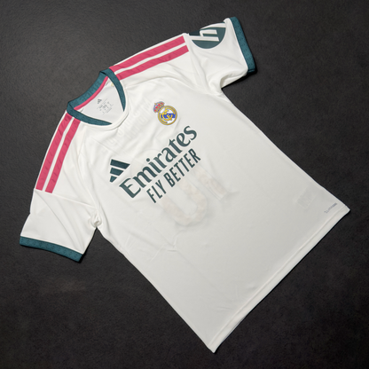 Front of the white adidas Real Madrid home jersey with the club crest and Emirates Fly Better sponsor