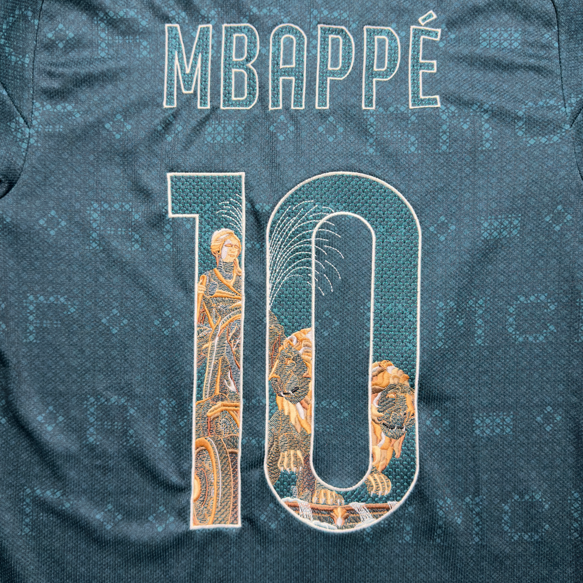 Mbappé name and number 10 on the green away jersey, with the Cibeles statue, her chariot and lions embroidered inside the numbers