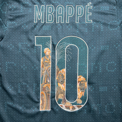Mbappé name and number 10 on the green away jersey, with the Cibeles statue, her chariot and lions embroidered inside the numbers