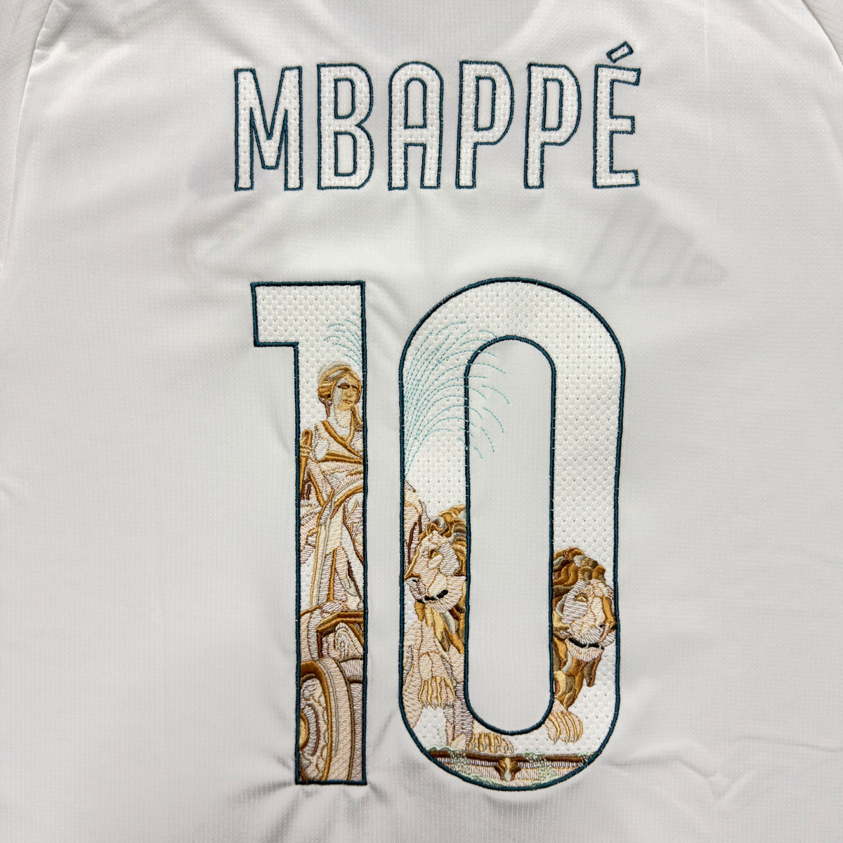 Mbappé name and number 10 with the Cibeles statue, her chariot and lions embroidered inside the numbers