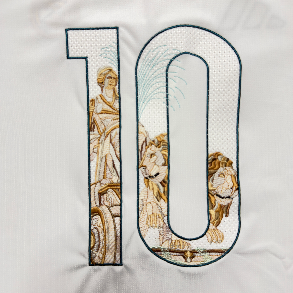Close-up of the embroidered 10: the Cibeles statue and chariot in the 1, the lions and the fountain's rising jet of water in the 0