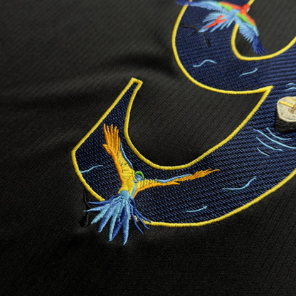Close-up of embroidered macaws in flight across the top of the 9