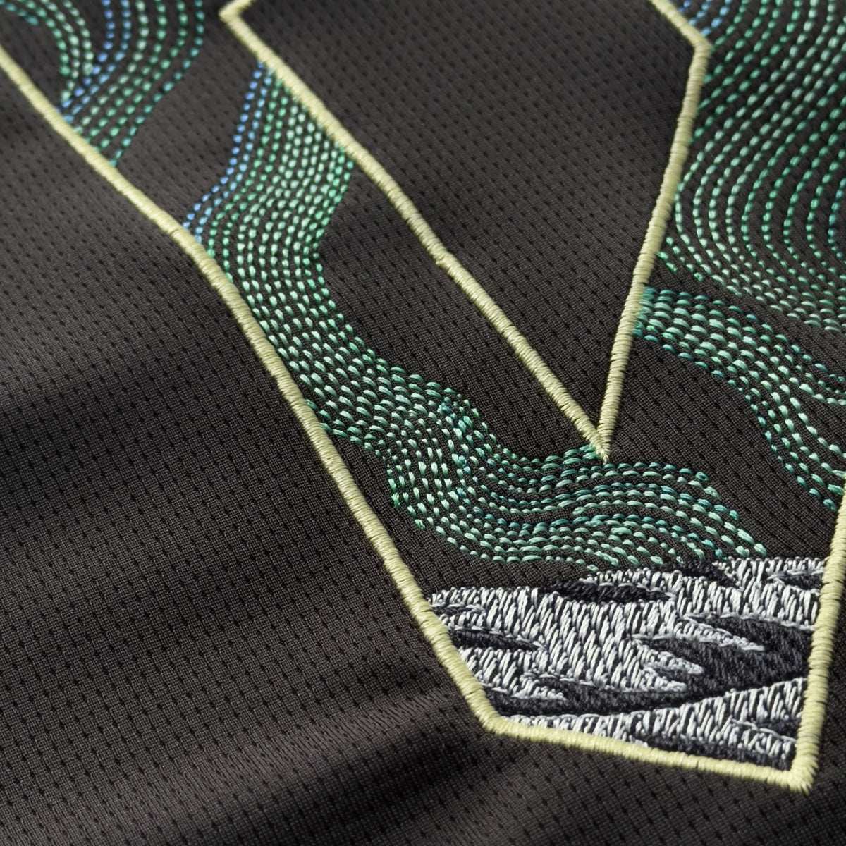 Detail of green, teal and blue aurora stitching flowing into a grey mountain on the 9