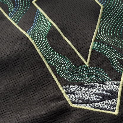Detail of green, teal and blue aurora stitching flowing into a grey mountain on the 9