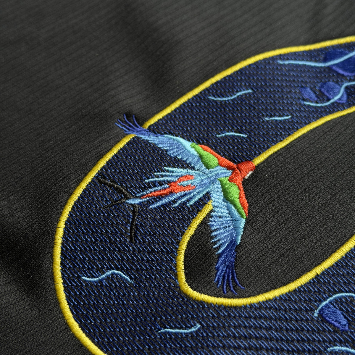 Close-up of a scarlet macaw stitched across the curve of the 9