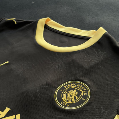 Manchester City crest and yellow collar on the black away jersey with tonal bee pattern
