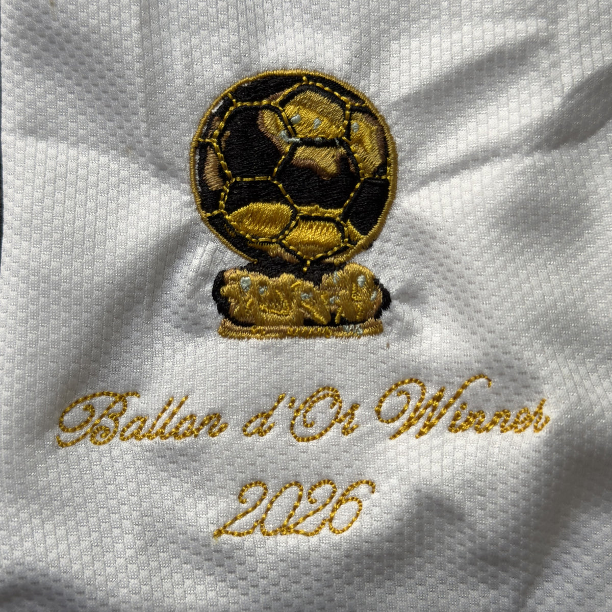 Close-up of the embroidered gold Ballon d'Or trophy patch with Ballon d'Or Winner 2026 in script