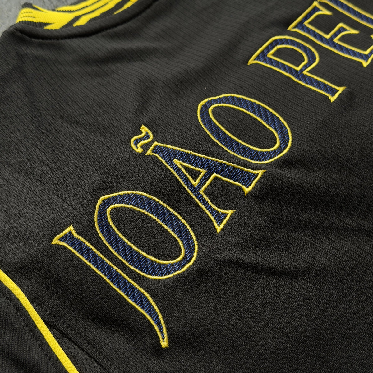 JOÃO PEDRO nameset in navy with a yellow outline on the black away jersey
