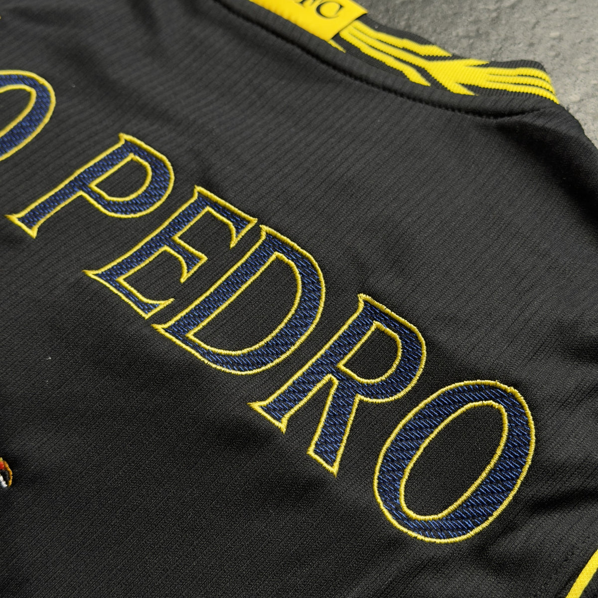 Close-up of the PEDRO lettering stitched in navy and yellow