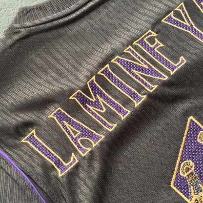 Detail of LAMINE in gold-outlined modernista lettering with a purple mesh fill