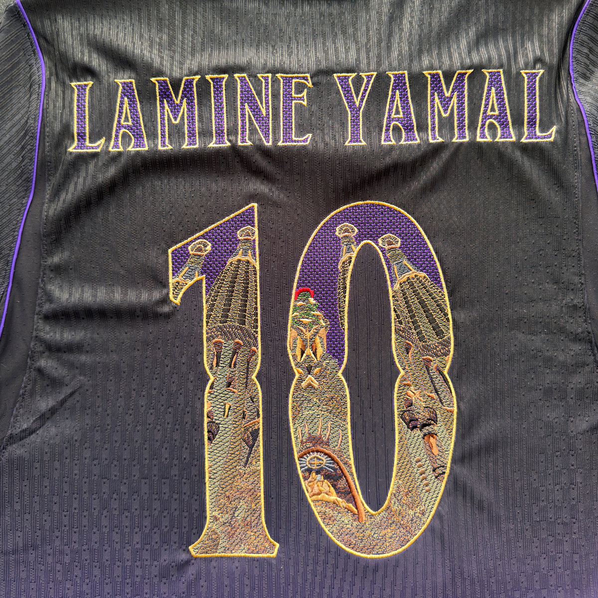 Close-up of the embroidered back: LAMINE YAMAL in gold modernista lettering above the Sagrada Família 10